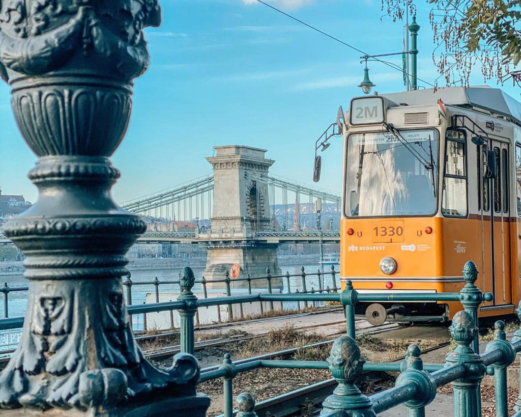 A yellow tram moves through the streets of Budapest.