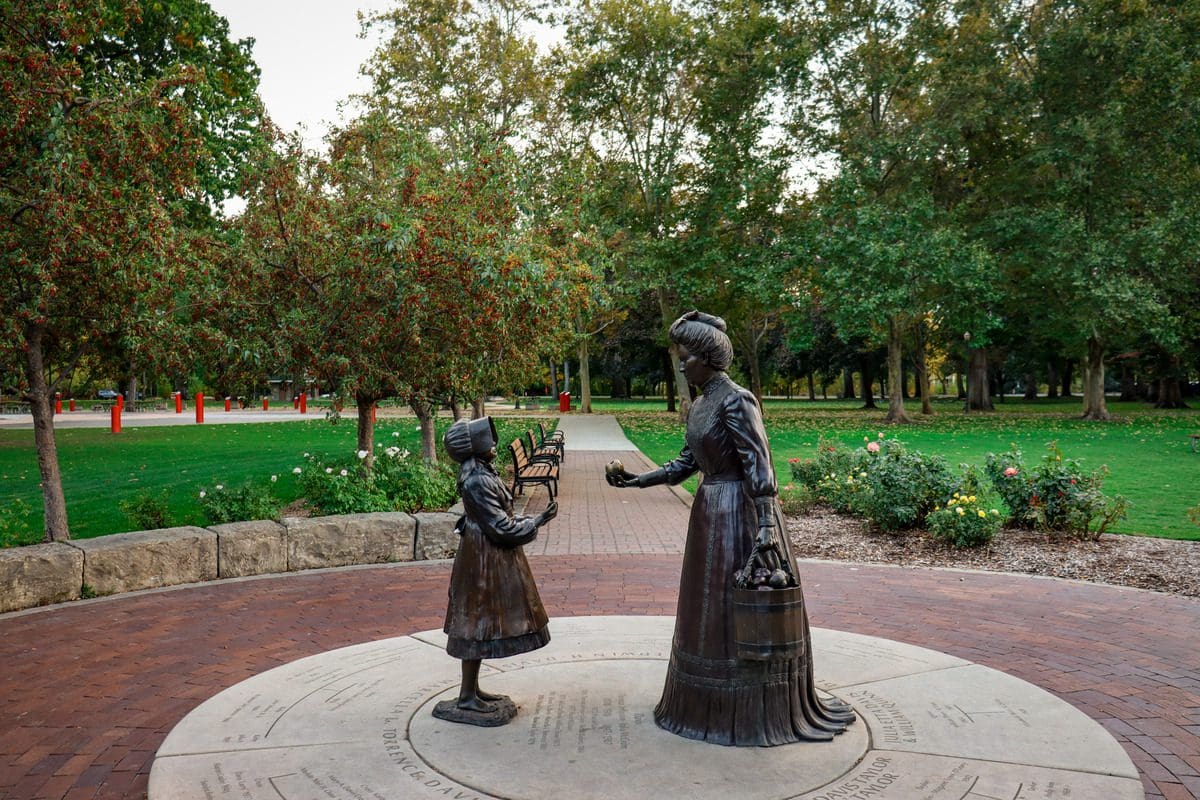 A statue of Julia Davis handing a flower to a young child at Julia Davis Park in Boise, one of the best affordable summer vacations in the United States with kids.