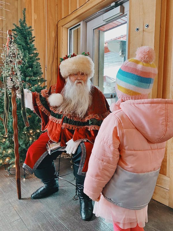 A young girl speaks with Santa at the Frankenmuth Farmers Market ChristKindMarkt, one of the best budget-friendly Christmas destinations in the US for families.