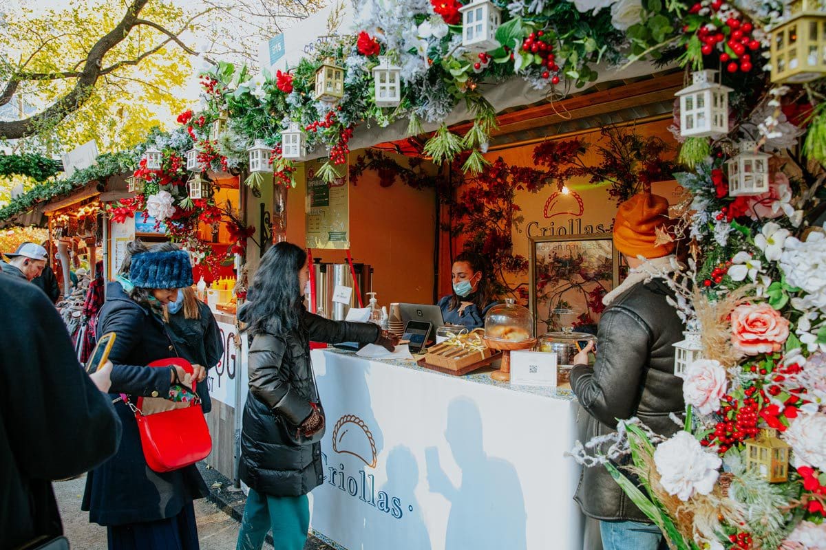 Several people make a purchase at a vendor stall at Columbus Circle Holiday Market, one of the best christmas markets in the United States for families.
