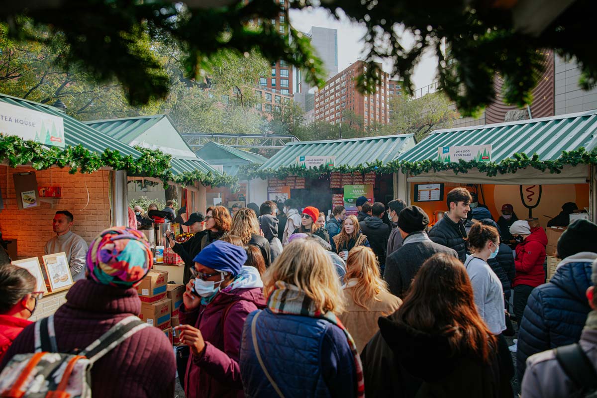 A crowd of people meander through a row of vendors at Union Square Holiday Market, one of the best christmas markets in the United States for families.