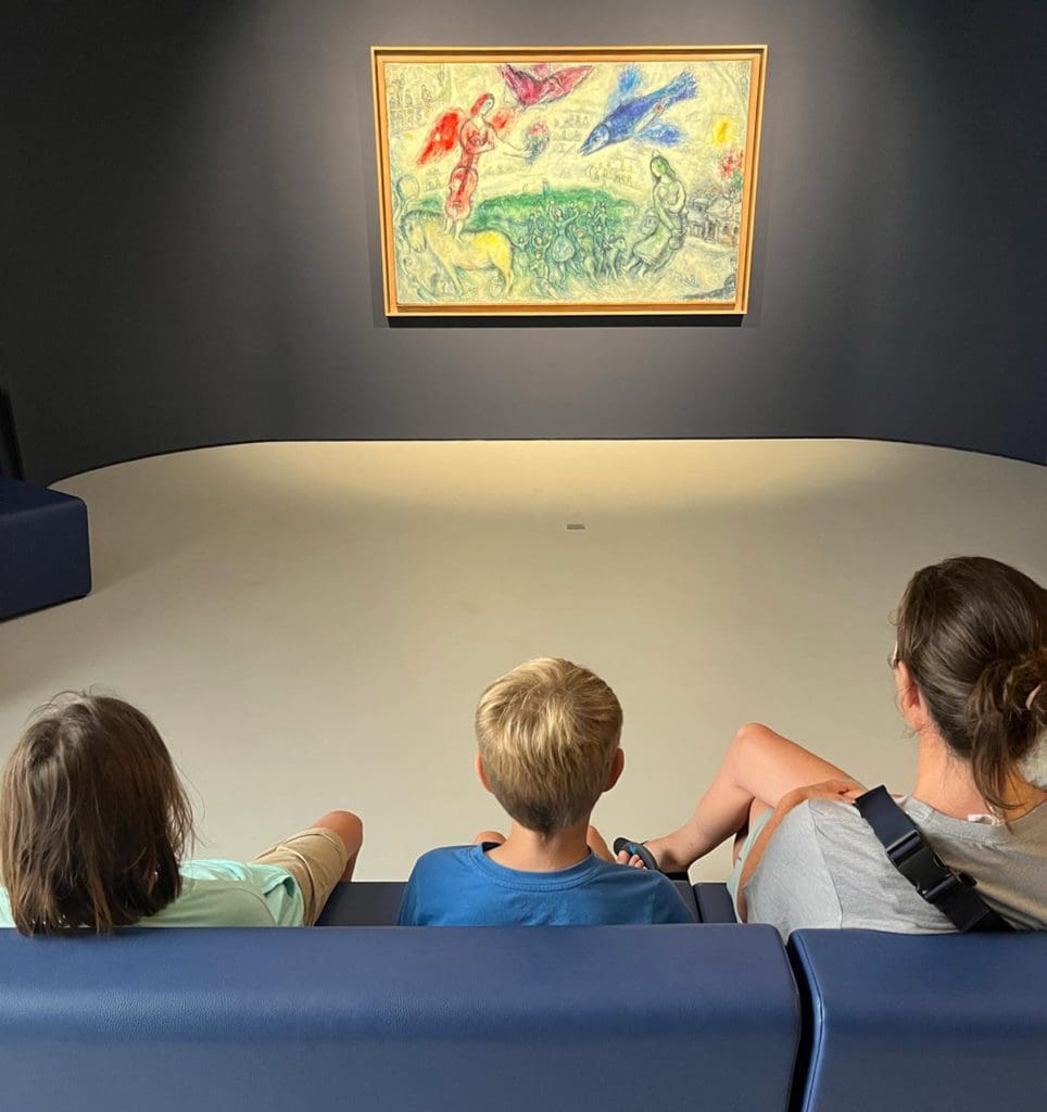 A mom and two kids enjoy a painting within the Musee d'Art Moderne, one of the best museums in France with kids.