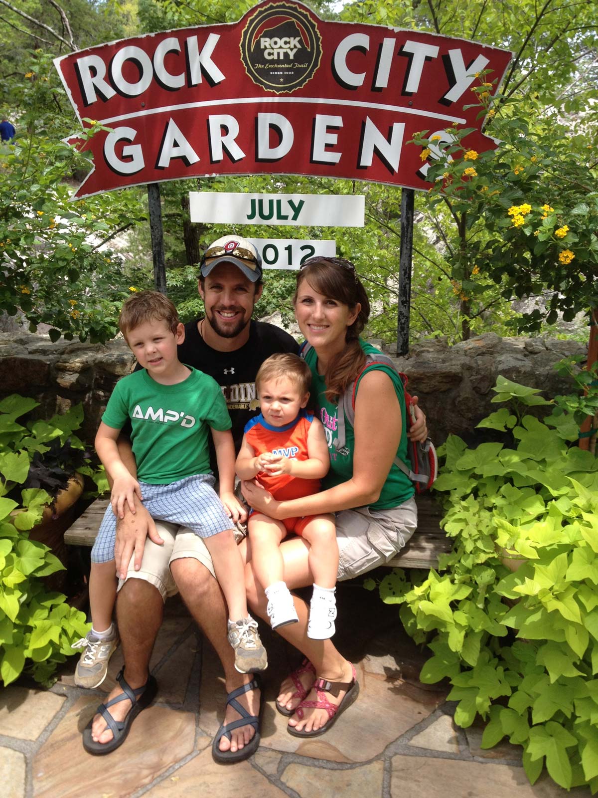 A family of four sits together on a bench at Rock City.