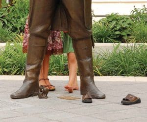 Kids feet shown behind the feet of a statue found while exploring Heritage Green, one of the best things to do in Greenville, South Carolina with kids.