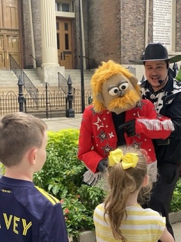 Two kids listen to a guide with Puppet City Tours Nashville share stories about the city.