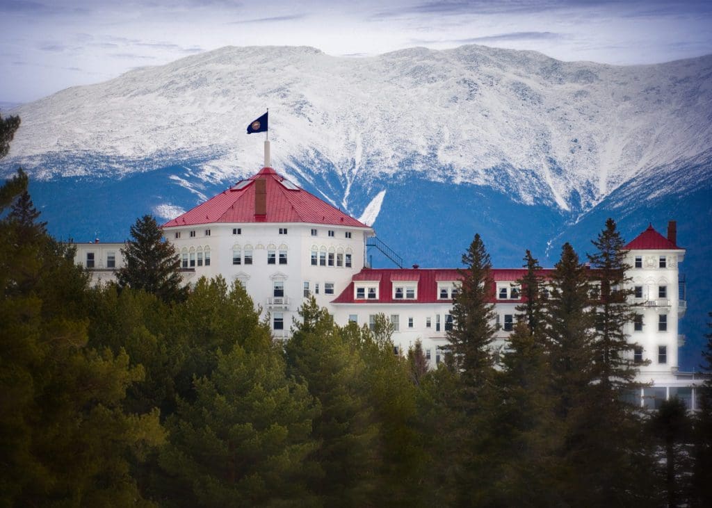 The iconic white resort with a red roof at Bretton Woods Ski Resort in the snow.