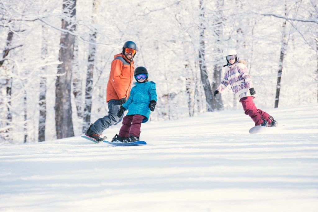 A parent and two kids race down an alpine trail at Smugglers' Notch Resort.