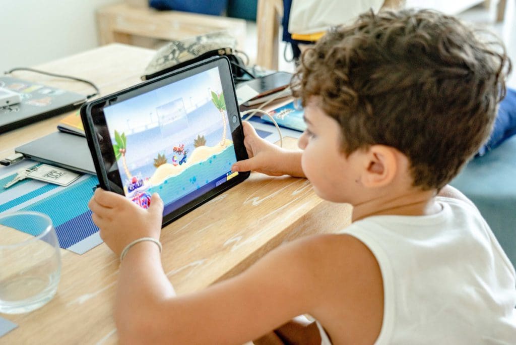 A young boy plays a game on an iPad, which area a great way to keep kids entertained while traveling.