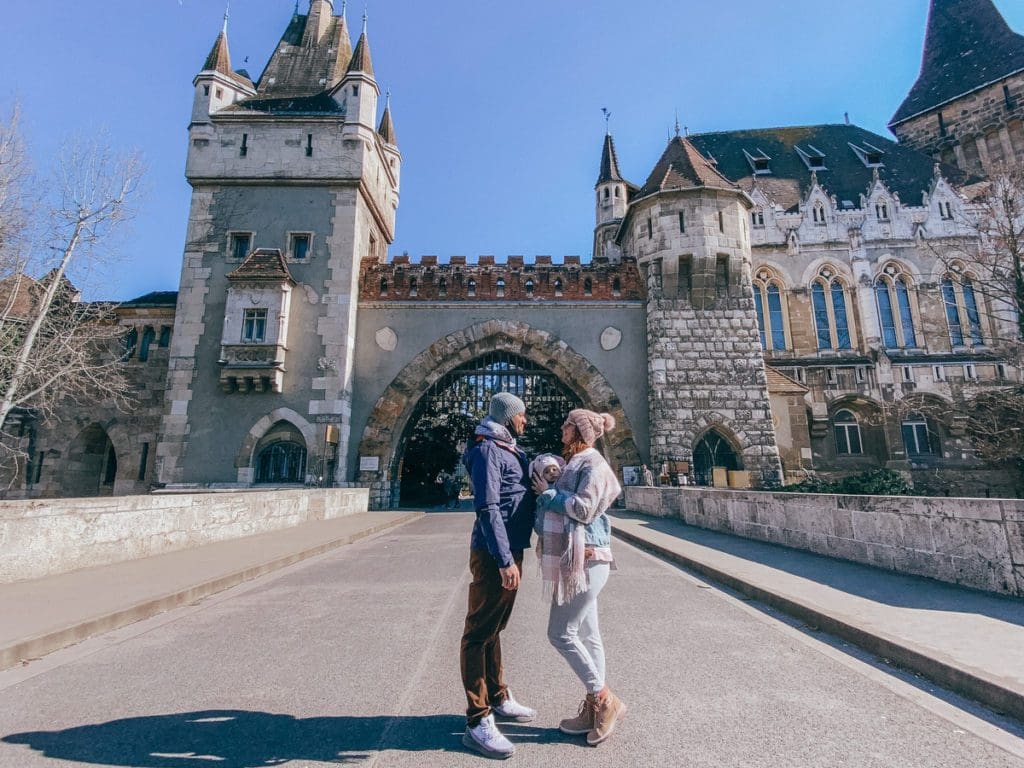 A family of three stands in front of the magical Vajdahunyad Castle, one of the best things to do in Budapest with kids.