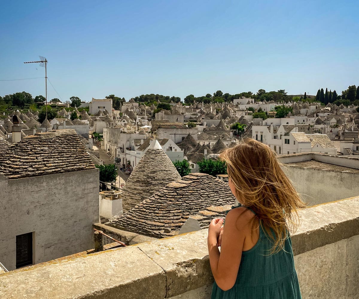 A young girl looks out over the rooftops of the famous trulli of Alberobello, one of the best things to do in Puglia with kids.