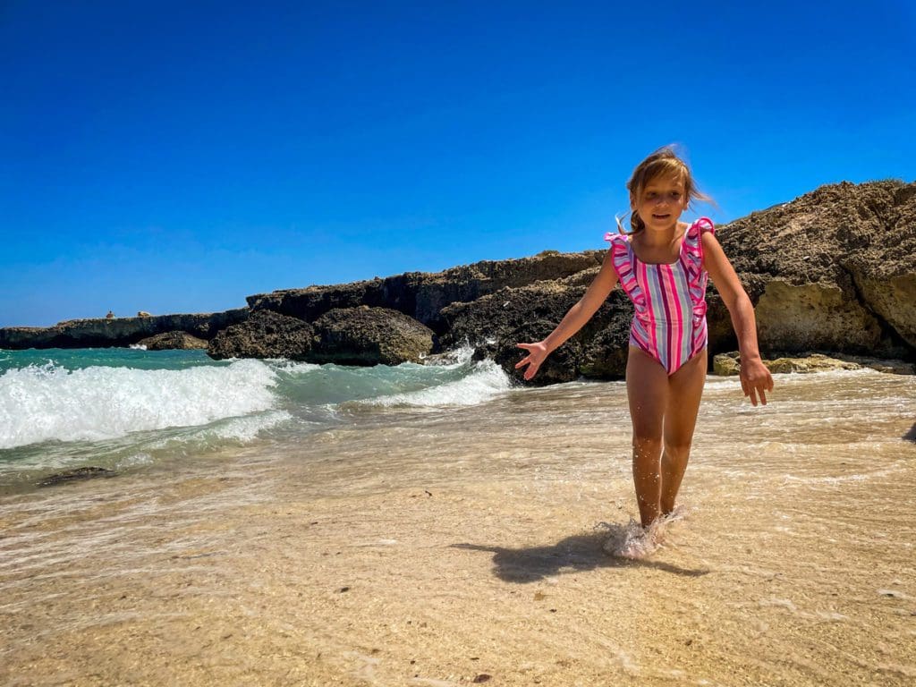 A young girl runs along a beach in Puglia.