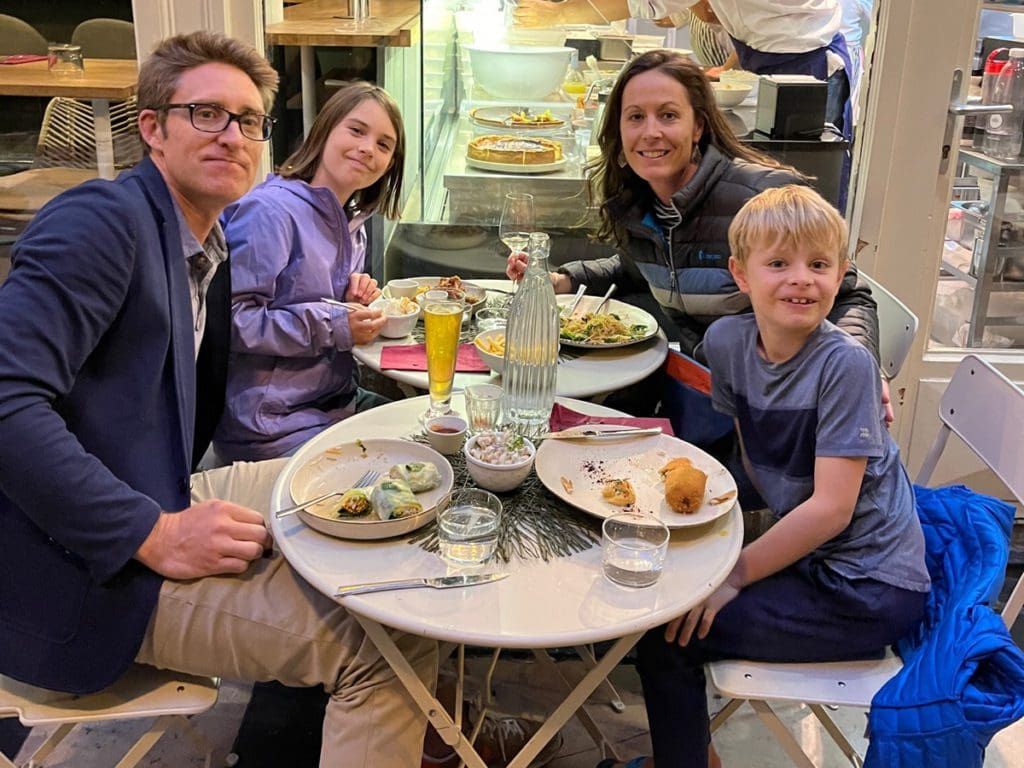 A family of four sits together having dinner in Paris.