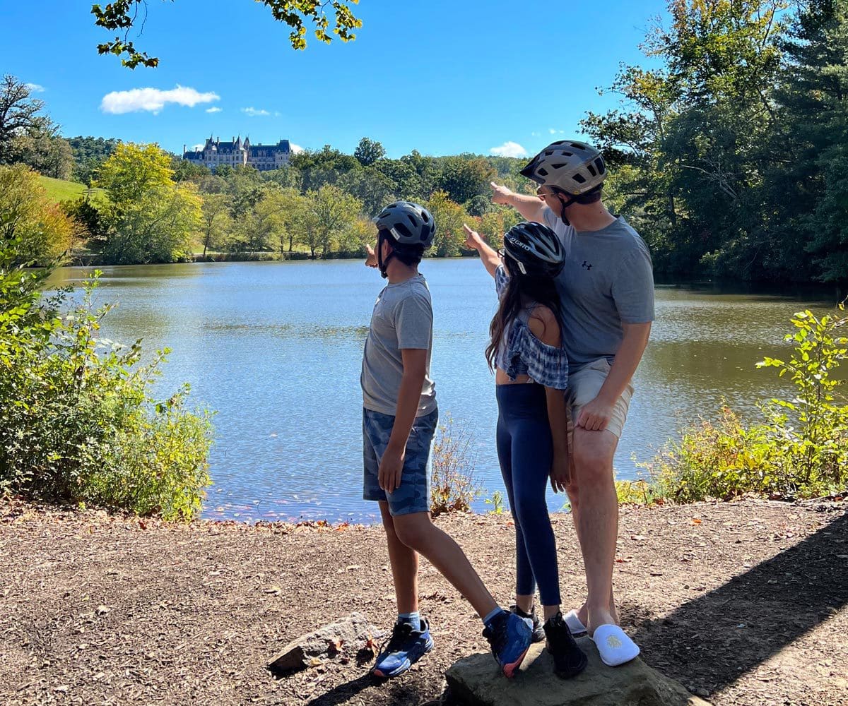 A dad and his two kids look out onto a scenic pond in Asheville, North Carolina.