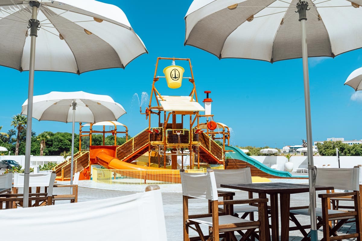 A colorful pool playground, with surrounding umbrella areas, at Mangrove Beach Corendon Curacao All-Inclusive Resort, Curio Collection, one of the best Curacao resorts with kids.