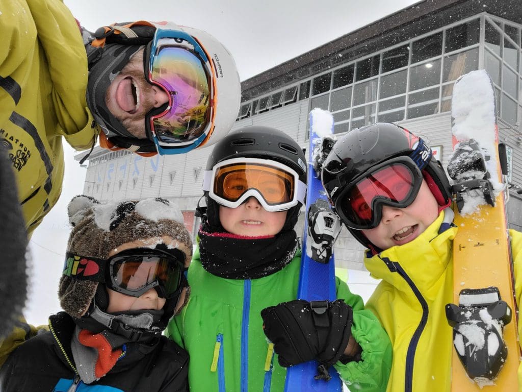 A family of four wearing ski gear in Japan smile together after a day of skiing.