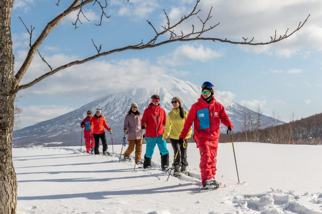 A group of people ski across a trail at Niseko United.