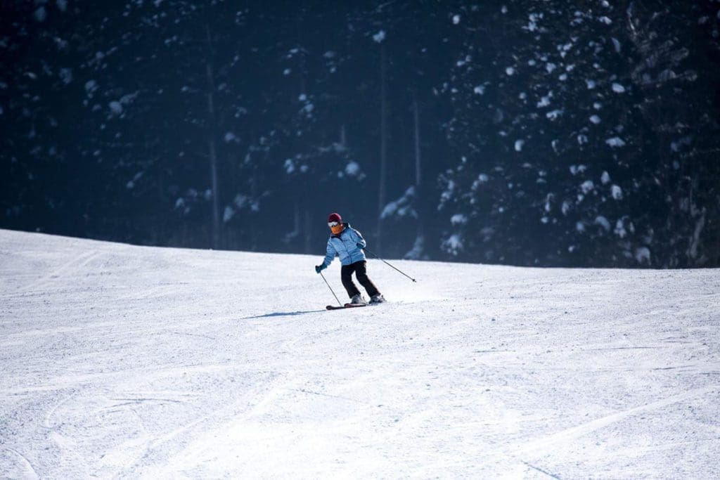 A solo person flies down an alpine trail in the snow at Nozawa Onsen Ski Resort.