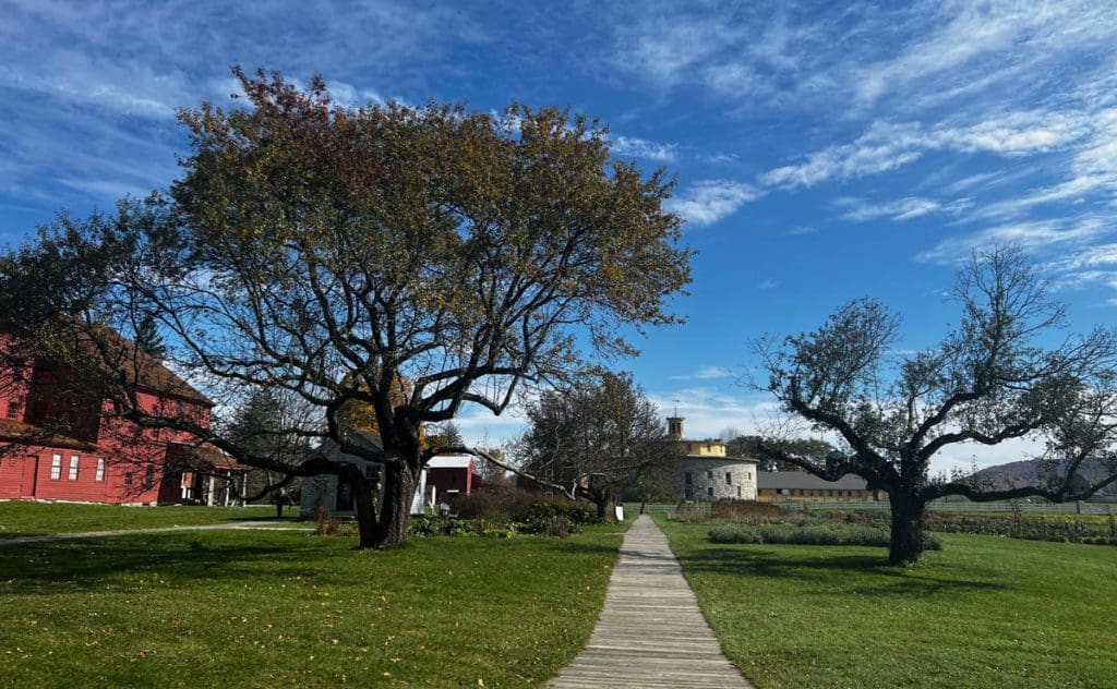 A sidewalk leads through the grounds of Hancock Shaker Village on a beautiful fall day.