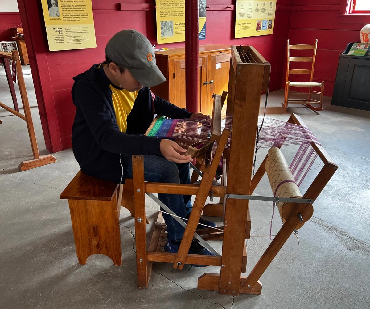 A young boy works a loom at the Hancock Shaker Village.
