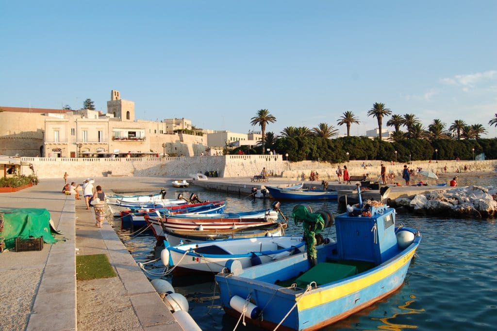 Boats line up along the port of Otranto with the Old City in the distance.