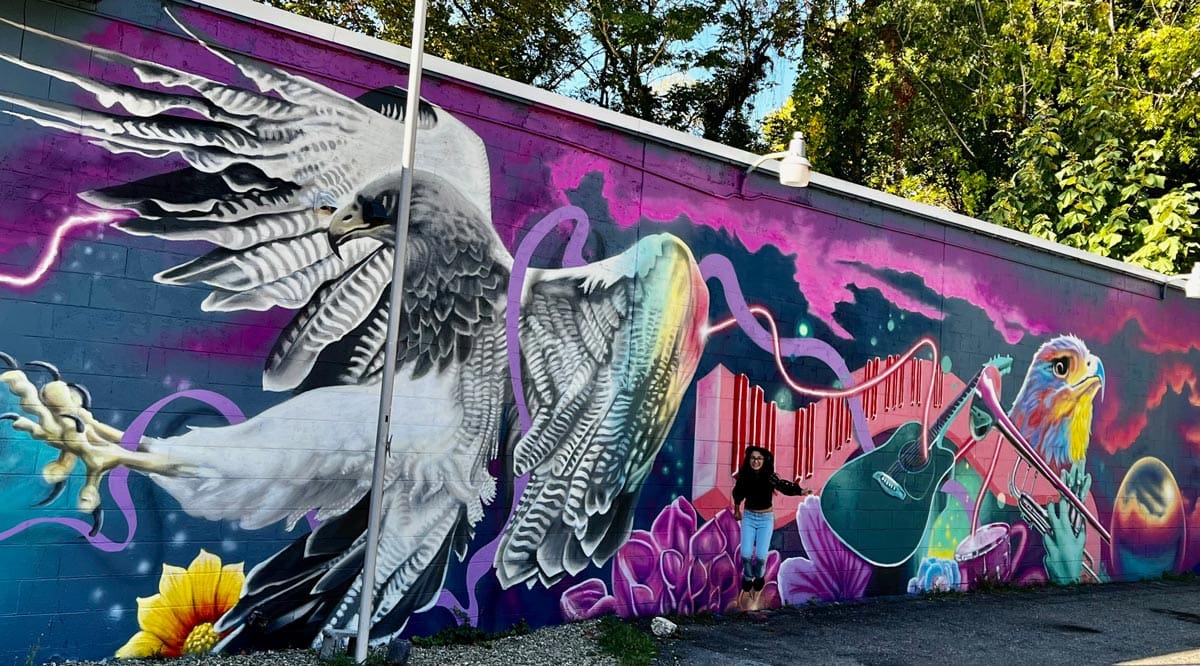 A young girl jumps in front of a vibrant graffiti mural in the Art District.