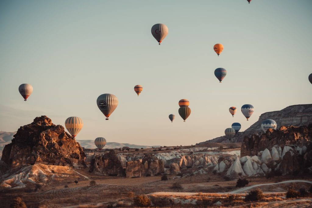Several colorful hot air balloons fly overhead in Cappadocia, knowing where to stay is part of learning all about Turkey with kids.