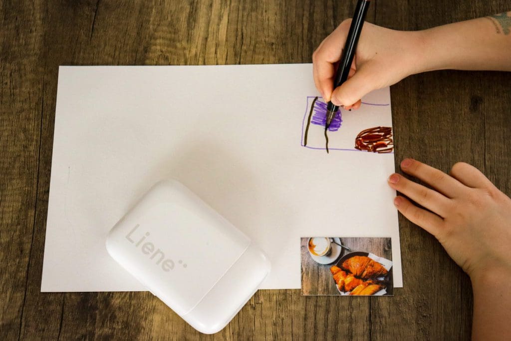 A young girl draws an image of a croissant from a printed picture.