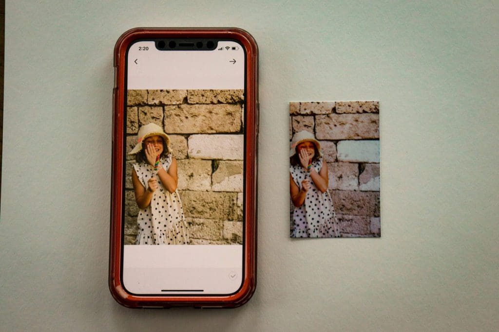A phone displaying an image, with a printed image next to it showing the image quality of the printed image.