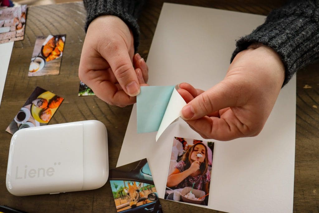 Adult hands pull apart a photo sticker sheet, while printing pictures for a travel diary.