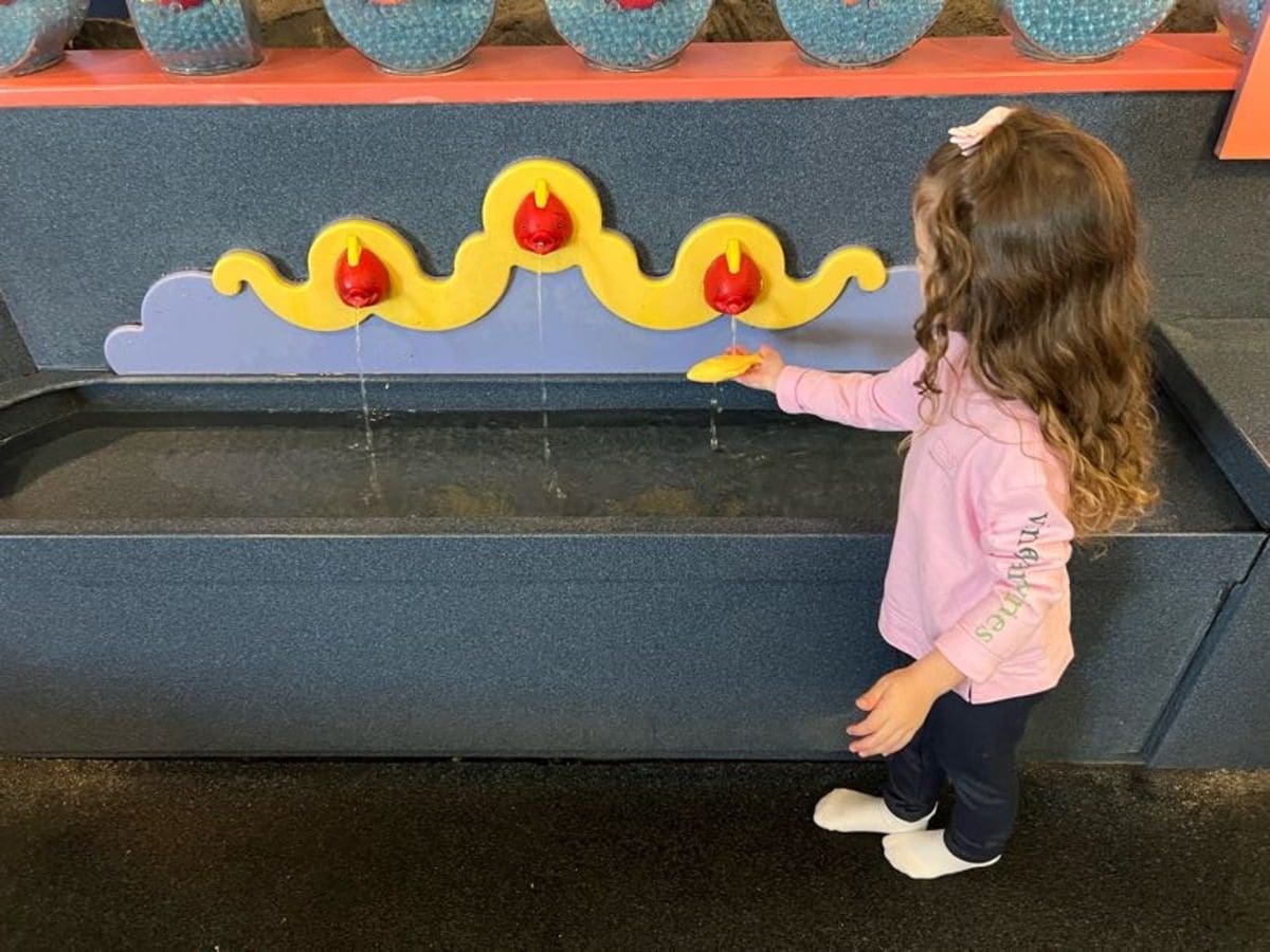 A young girl plays at a water table at Monterey Bay Aquarium.