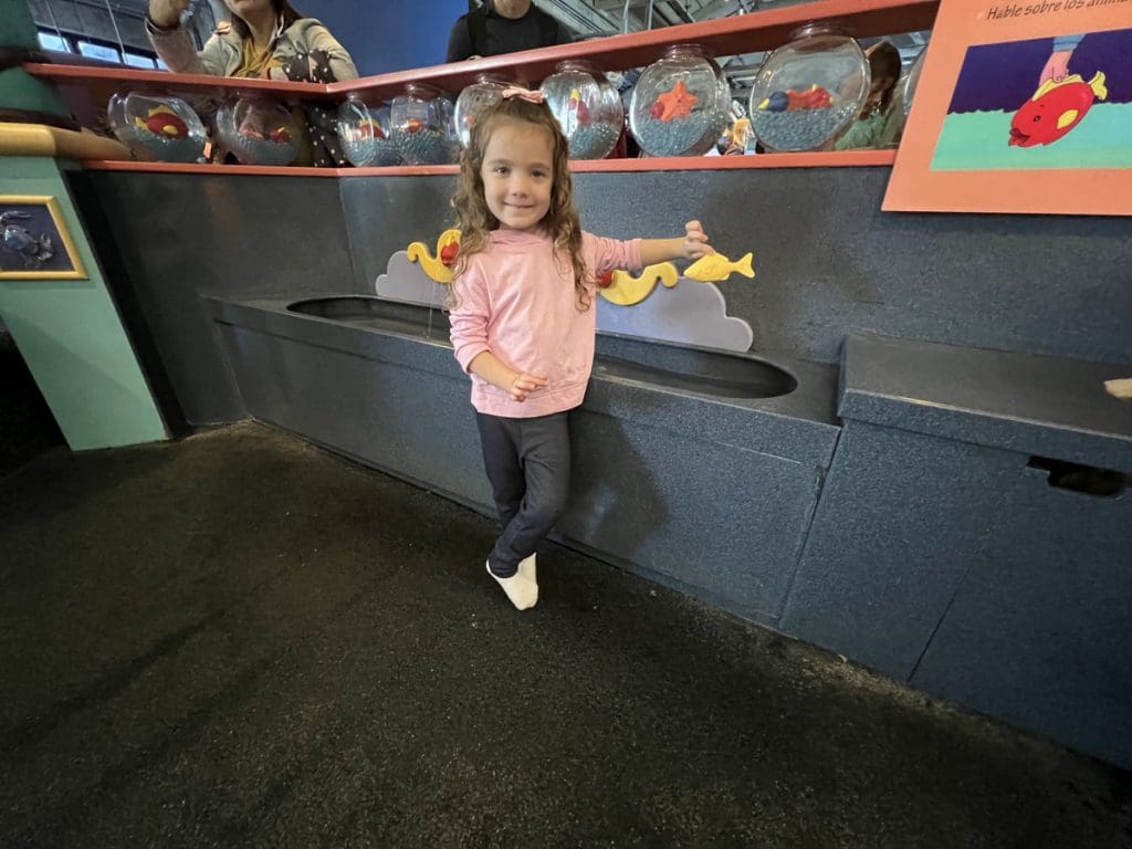 A young girl stands next to a water table at Monterey Bay.