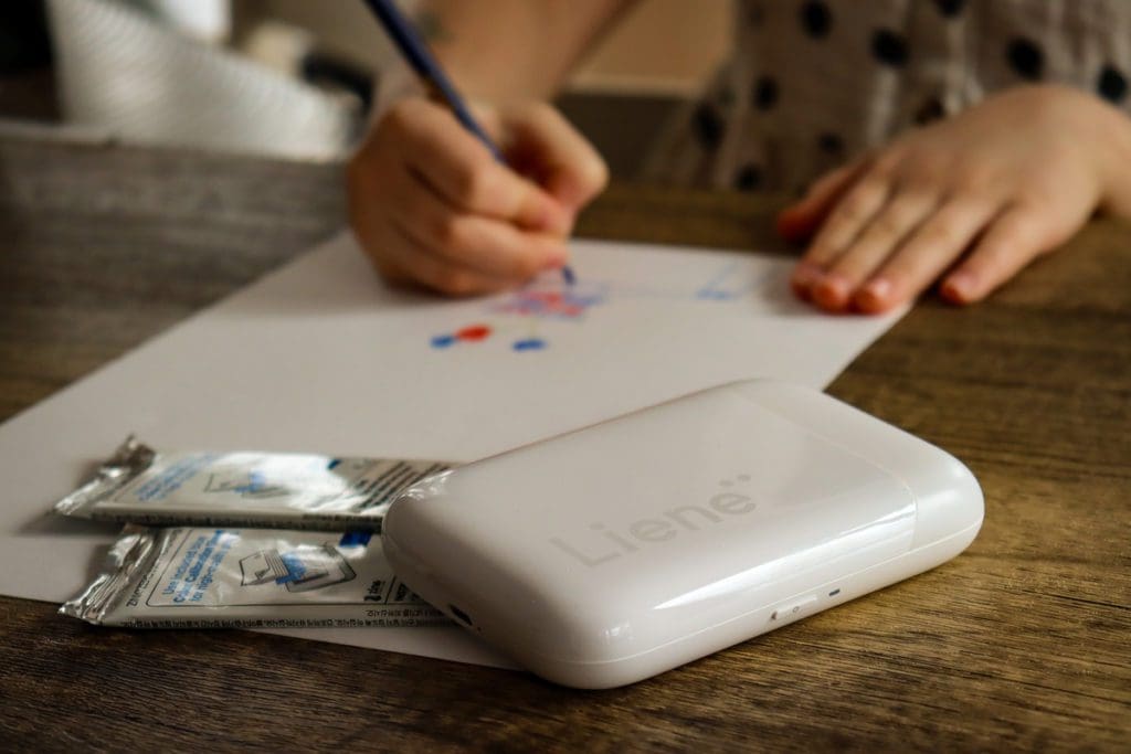 A young girl colors a picture using an image from a Liene Pearl Portable Photo Printer.