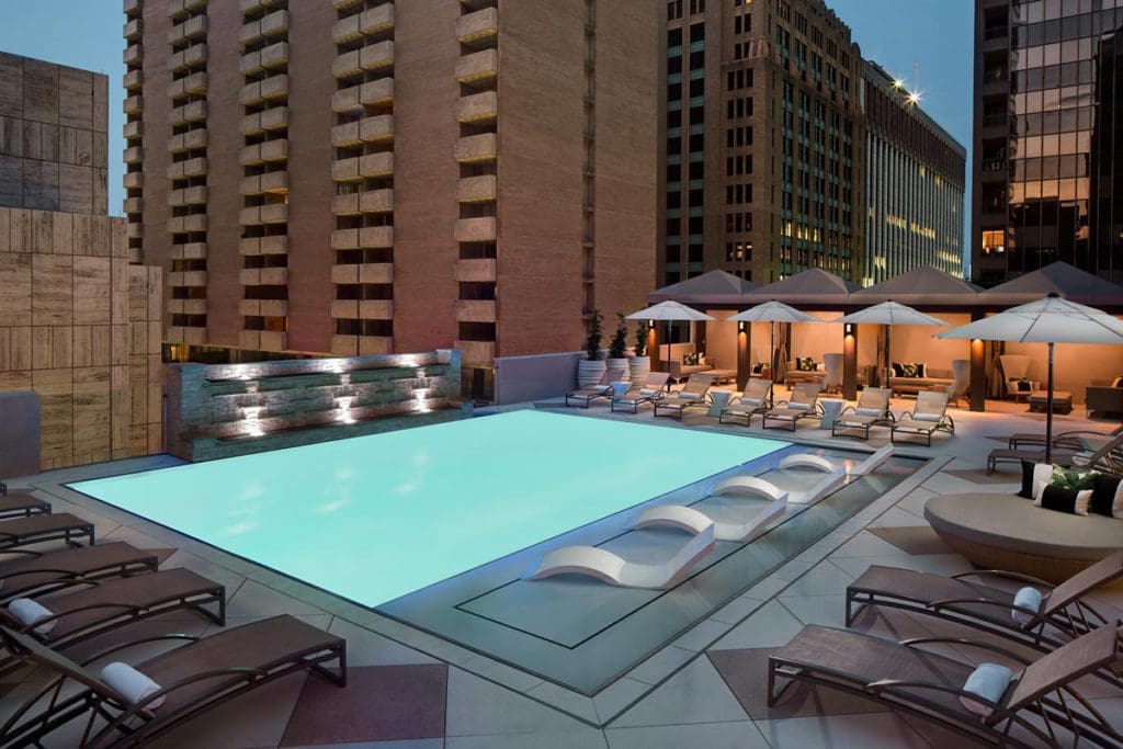 The outdoor pool on the terrace of The Adolphus, Autograph Collection Hotel at dusk, one of the best hotels in Dallas for families.