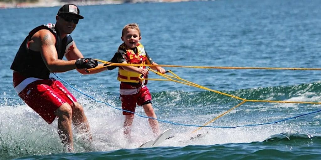 A water ski instructor guides a small child along the water at McKenzie Water Ski School.