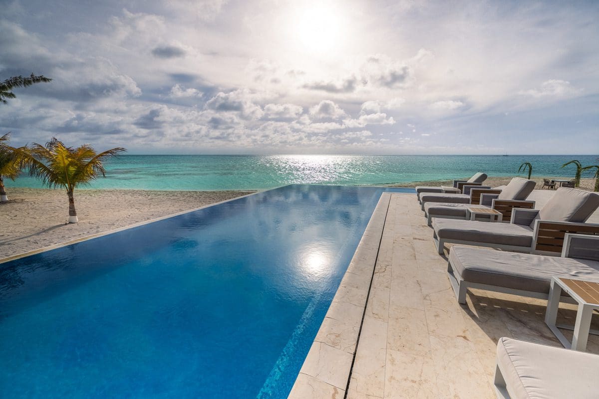 A pool, with poolside loungers along once side, stretches out toward the ocean at Manta Island Resort.