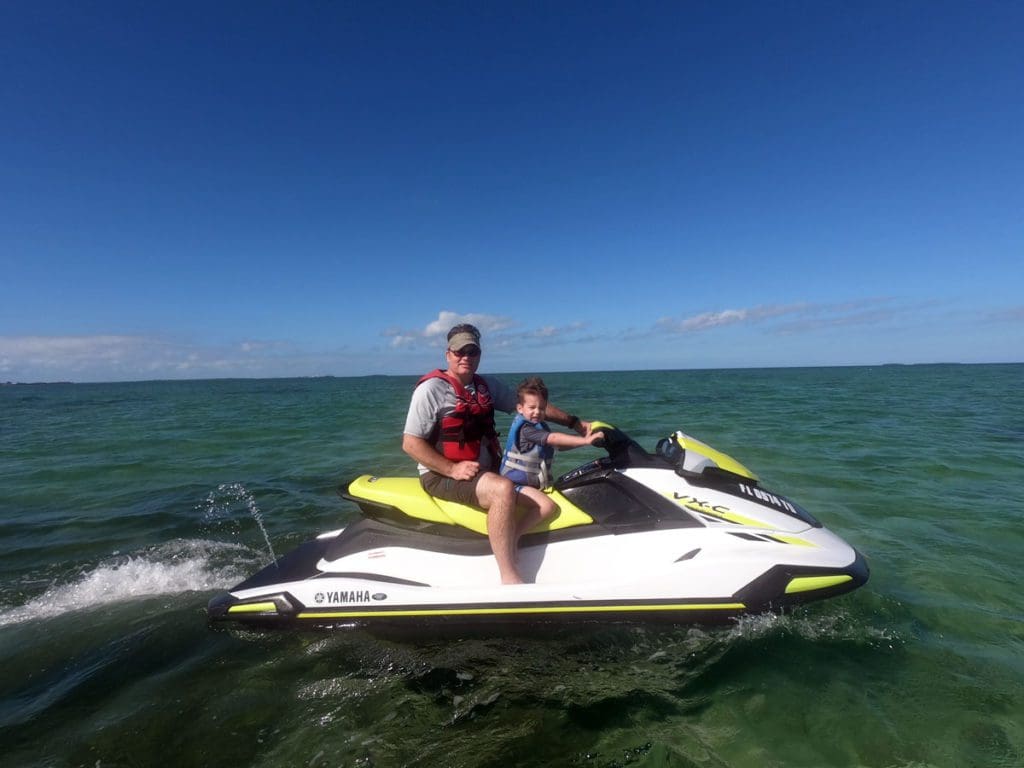 A dad and his young son ride a jet ski off-shore from Key West.
