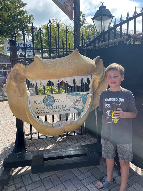 A young boy stands near the entrance sign to the Key West Aquarium.