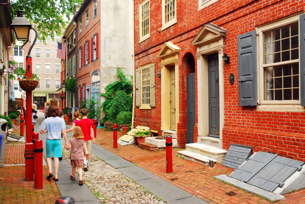 A family of three walks down a historic street in Philadelphia together.