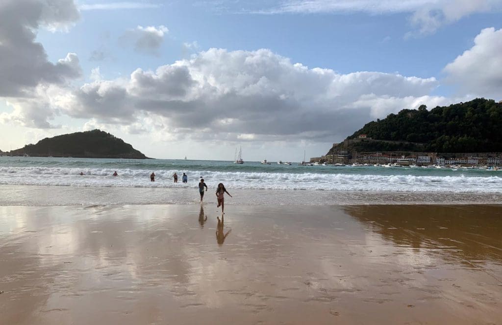 Kids running along a beach in Donostia-San Sebastian.