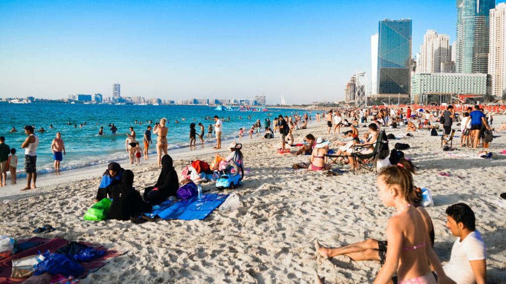 A beach full of beach goers in Dubai on a sunny day.
