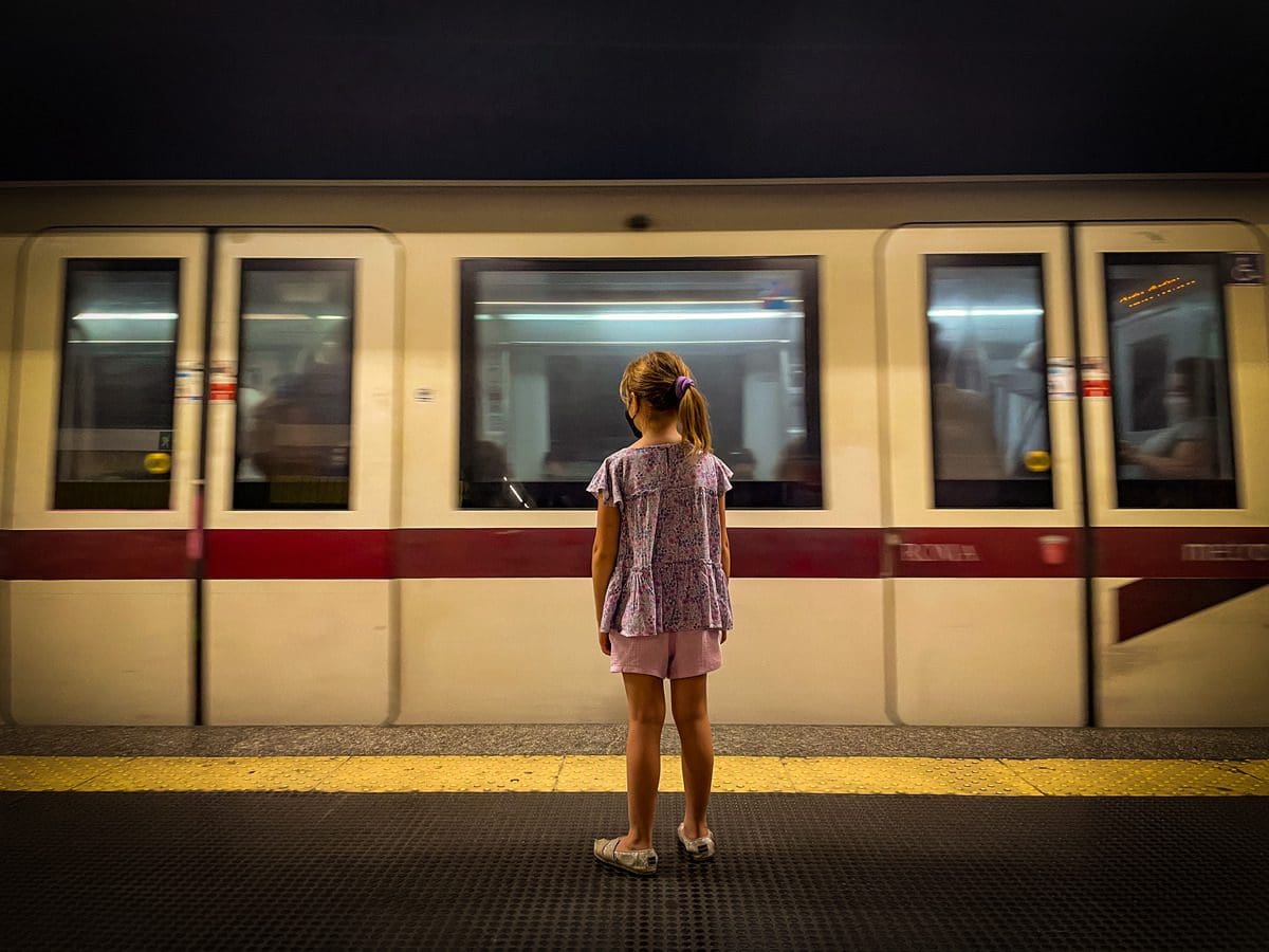 A young girl watches a Rome subway car whizz by.