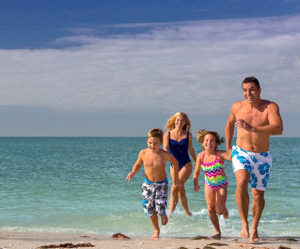 A family of four runs across the beach, while staying at Hyatt Regency Coconut Point Resort and Spa.