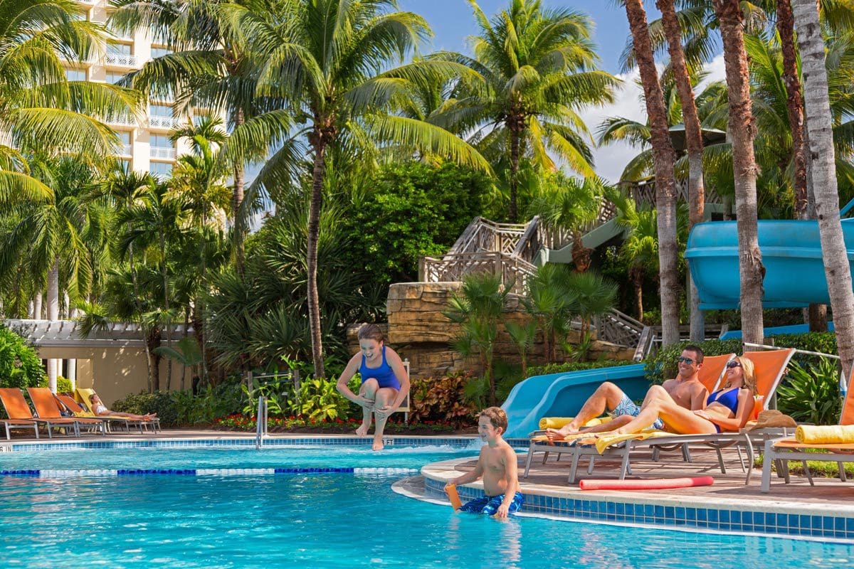 Kids splash in a pool, while their parents lounger nearby, at Hyatt Regency Coconut Point Resort and Spa, one of the best hotels in Naples for families.
