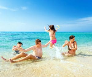 A family splashes in shallow water on a beach in Italy.