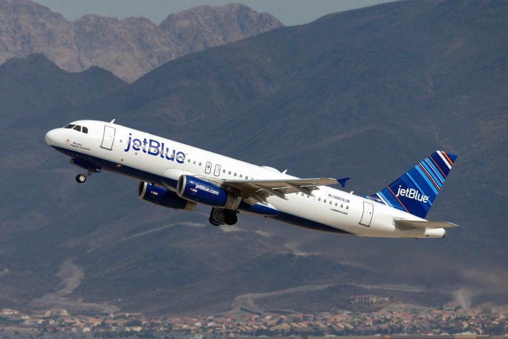 A JetBlue carrier takes off from an airport in the mountains.