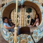 Two kids sit in a colorful carousel seat in Malaga.