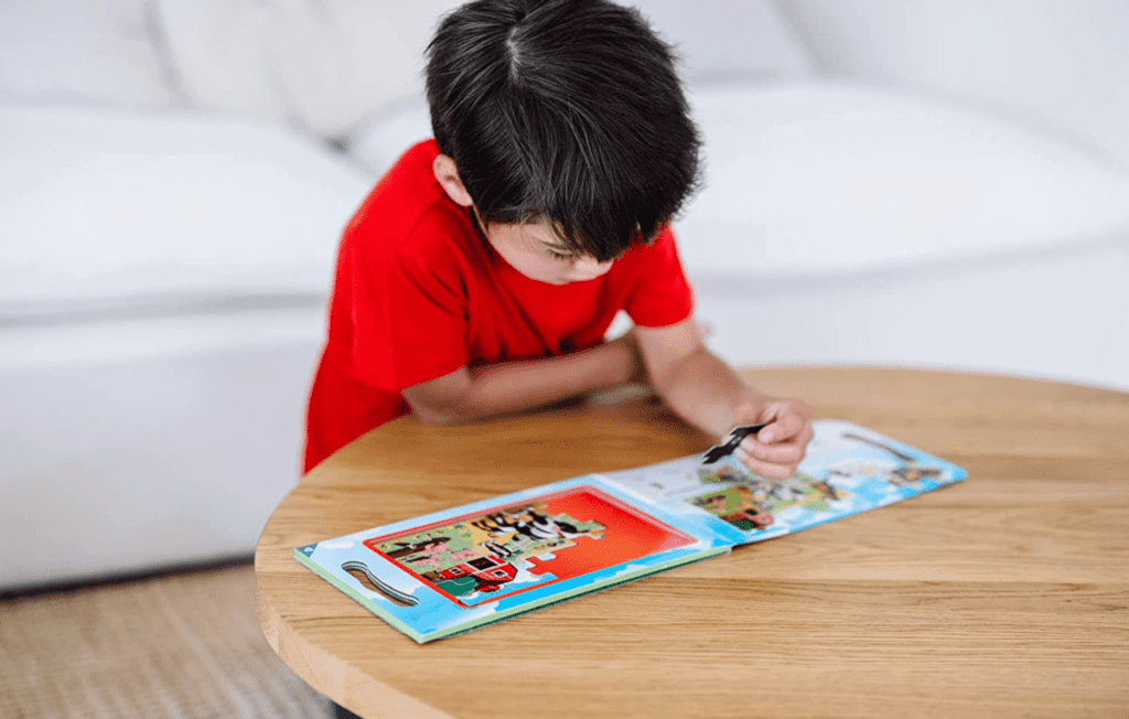 A young boy plays with a Melissa & Doug Take-Along magnetic jigsaw puzzle, a great way to keep kids entertained while traveling.