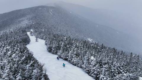 Two people ski down a trail at Sugarbush Mountain.