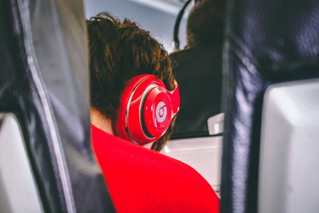 A teen boy listens to an audio book through headphones on a plane, audio books are a great way to keep kids entertained while traveling.