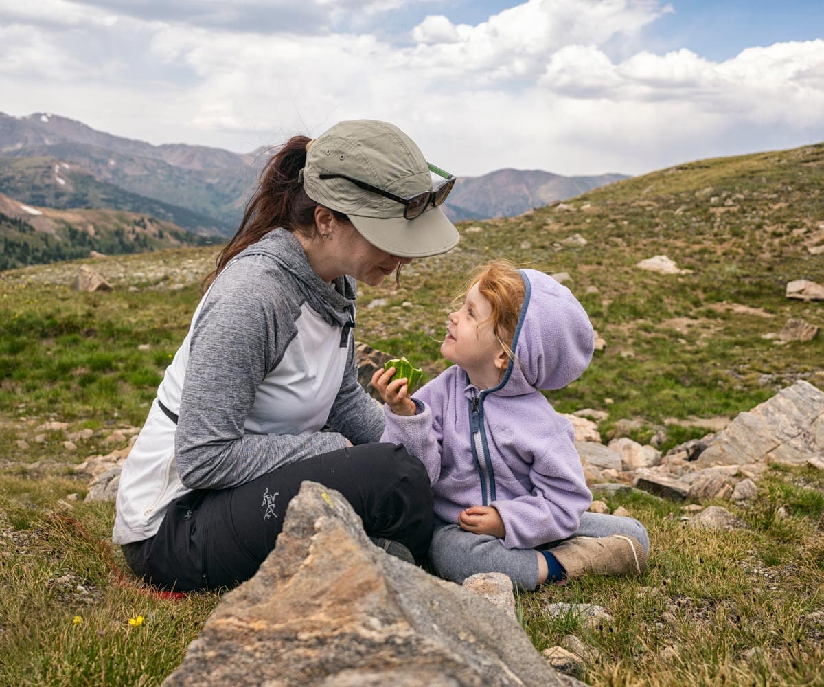 A mom and her young daughter enjoy a trail snack, while hiking in Denver.